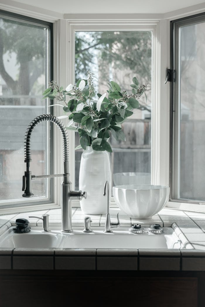 Bright kitchen with modern faucet and eucalyptus in a vase, creating a serene ambiance.